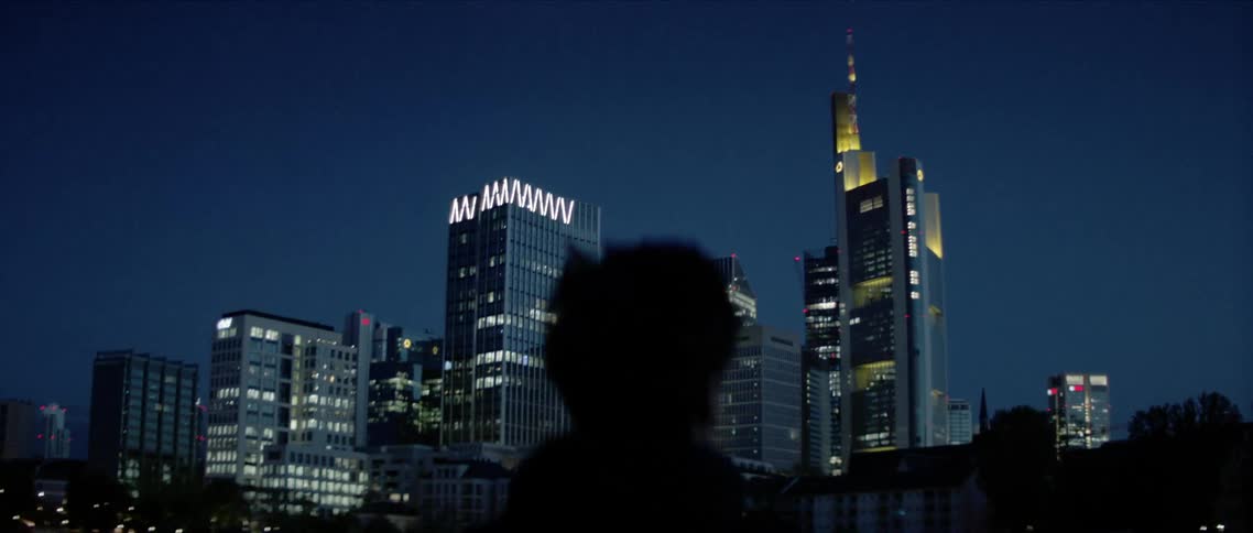 Silhouette of a man looking at a city skyline at night