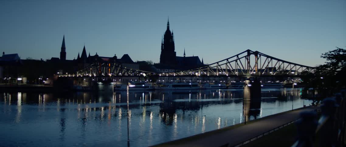City and lights from suspension bridge reflect from the river