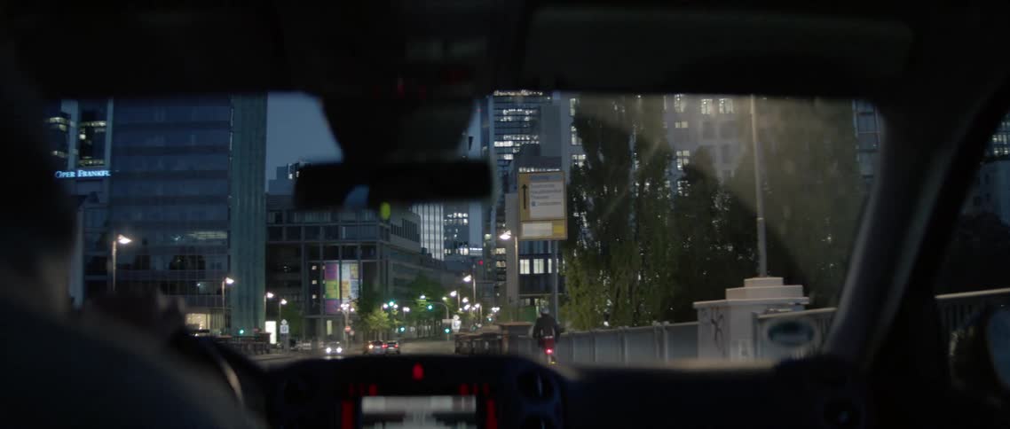 A person drives down the road towards the buildings