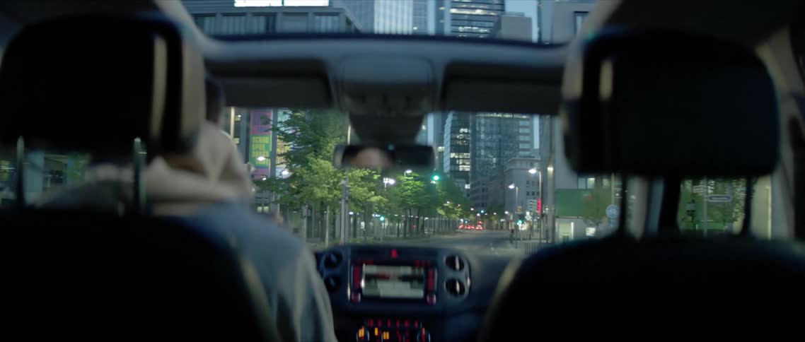 Man drives car along street past downtown skyscrapers