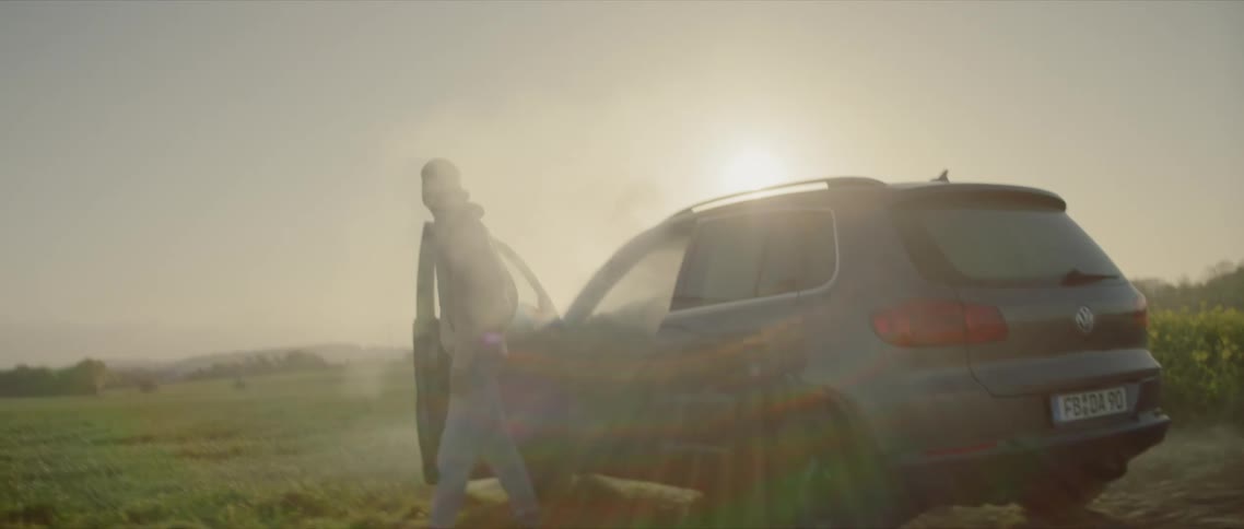 Man gets out of the smoke filled car in a wide open field