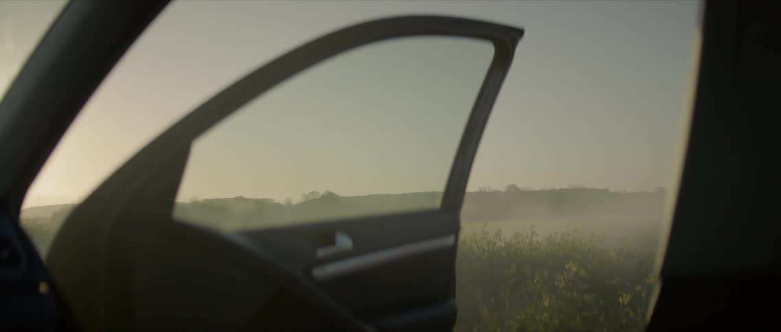 Wide open field landscape from the open door of the car