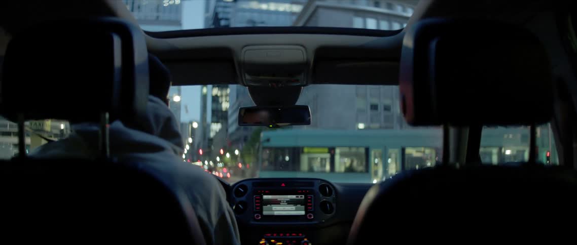 A man is driving a car through a downtown city