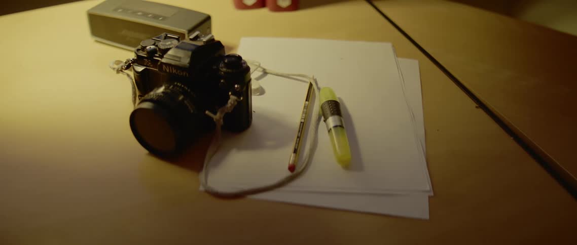 Camera lays on paper on table near pencil