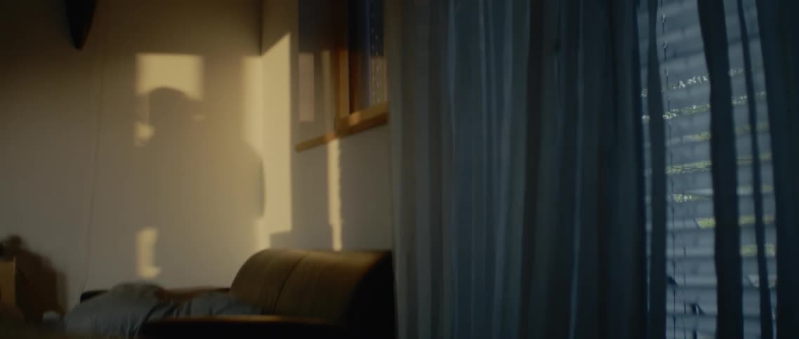 The shadow of the man wearing headphones and listening to music is reflected in the wall in a room