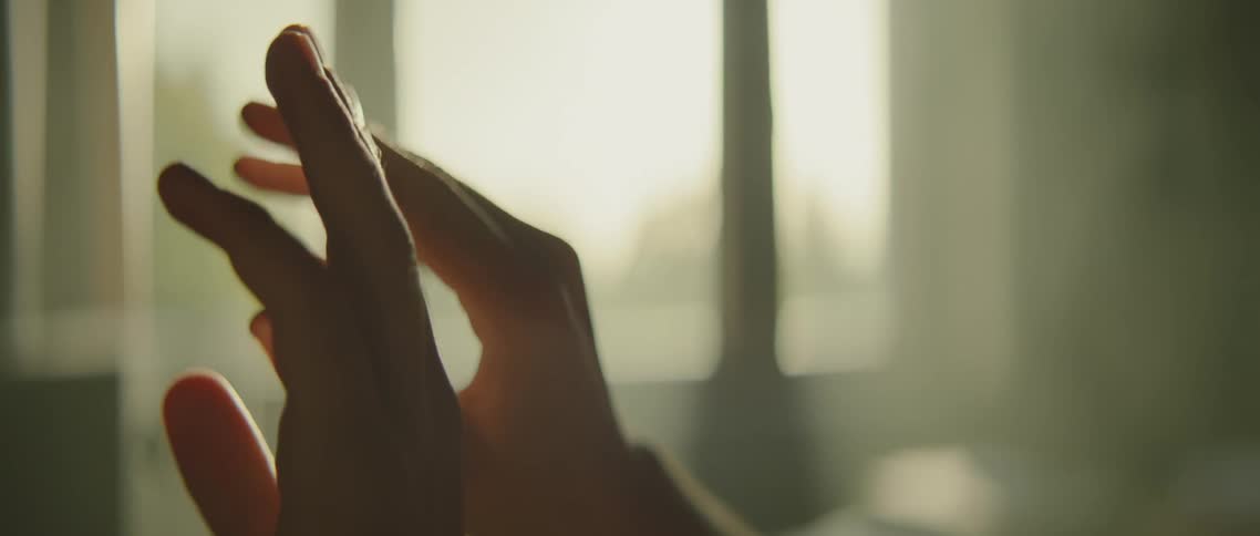 Person flexes their hands in the sun shining through the window