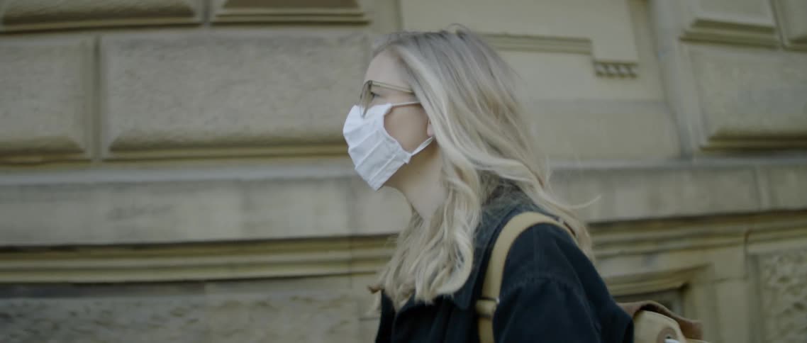 A teenager wearing a mask walks outside