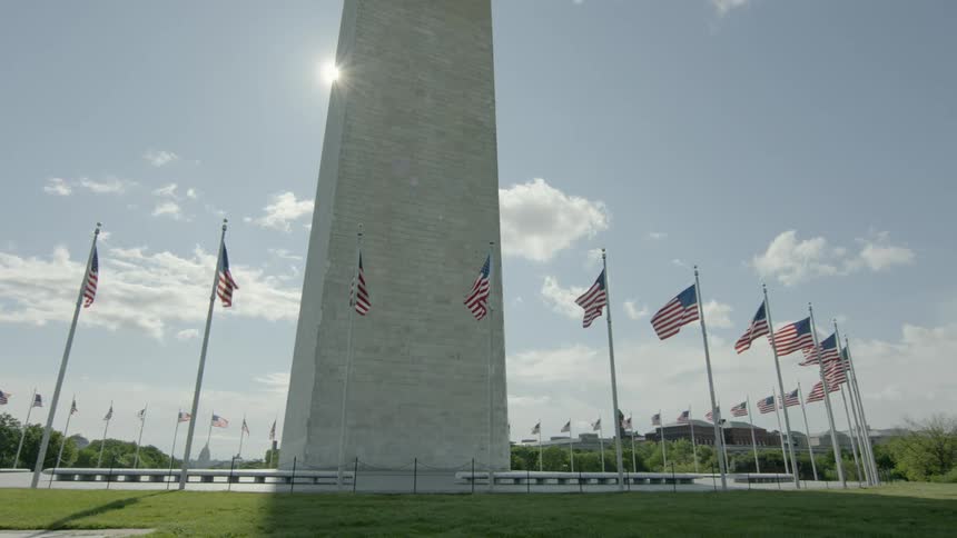 A tall government monument is surrounded by a ring of american flags