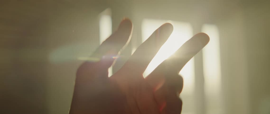 Hand flexes and reaches in sunlight entering through window