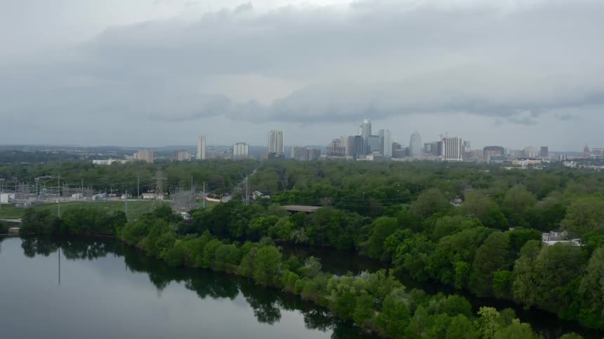 A pond with trees with the city skyline in the background