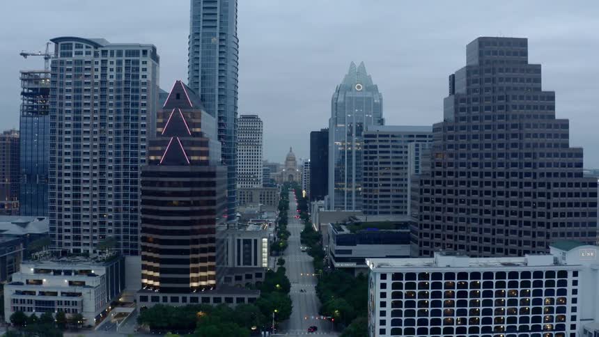 Only a few cars travel on a wide city street on a cloudy day