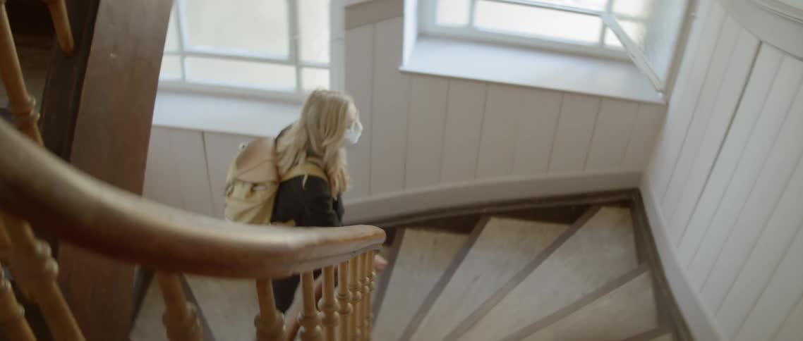 A girl with a mask on walks up the stairs