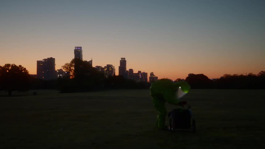 A person with a hazmat suit pulling a cart with a city skyline in the foreground