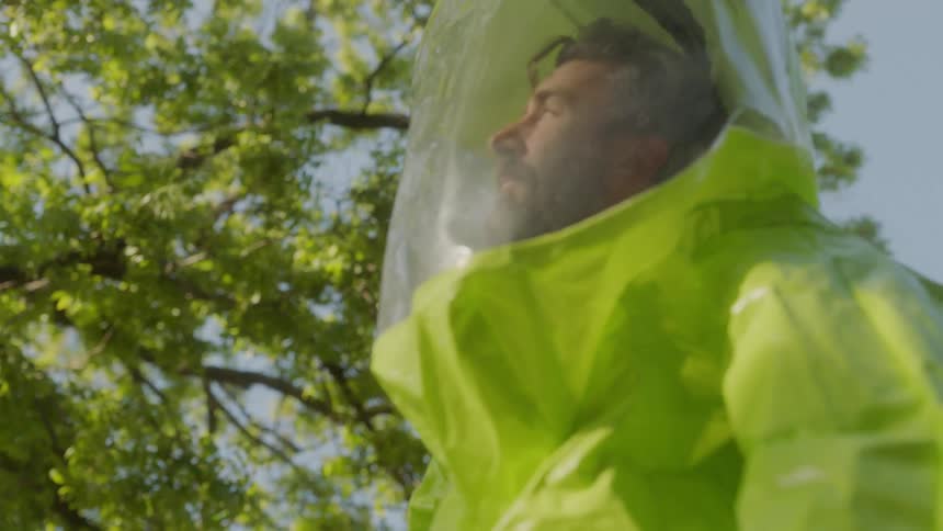 Man in hazmat suit by a tree