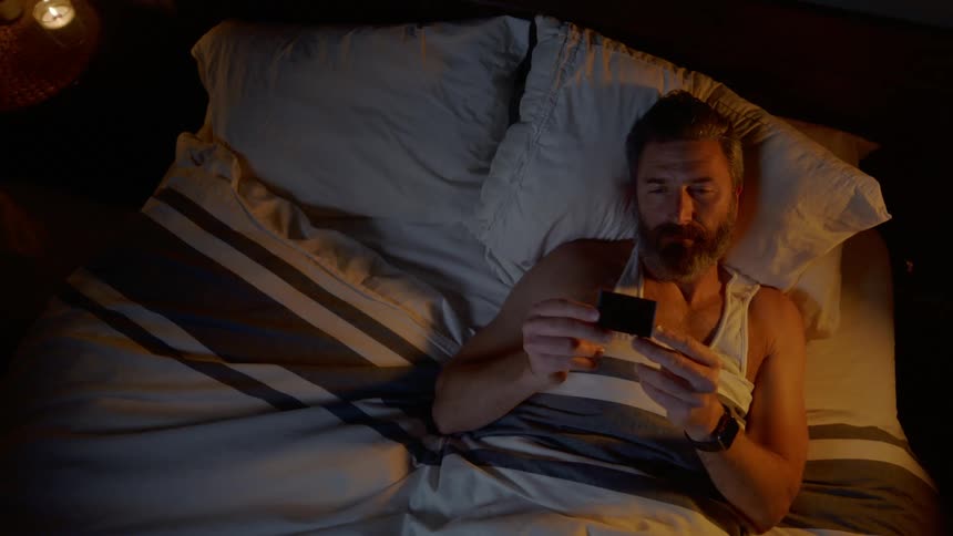 A man laying in bed watching a picture