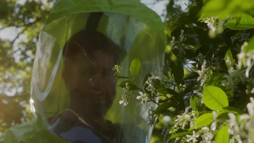 A man with a hazmat suit looking at a plant then walking away