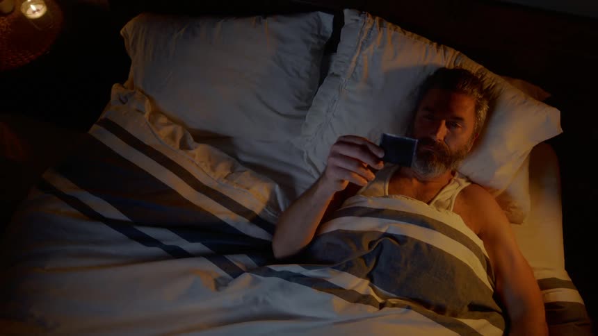 Man lying on the bed looks at the photograph in the bedroom