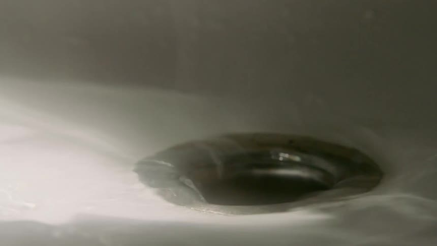 The water spins down the drain of the sink