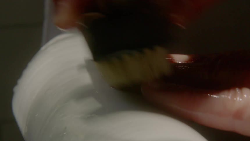 A person placing their hand in the edge of a bathtub and scrubbing it with a brush