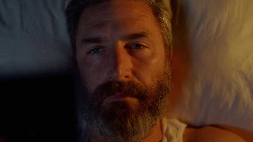 A man laying in bed looking at a picture