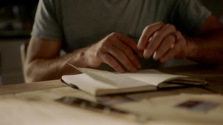 A man is writing in a journal
