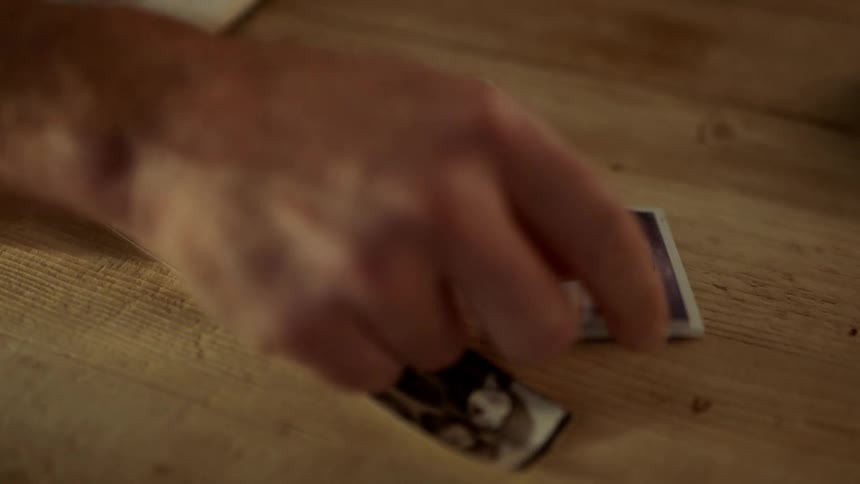 A persons hand putting down a picture on a table with other pictures