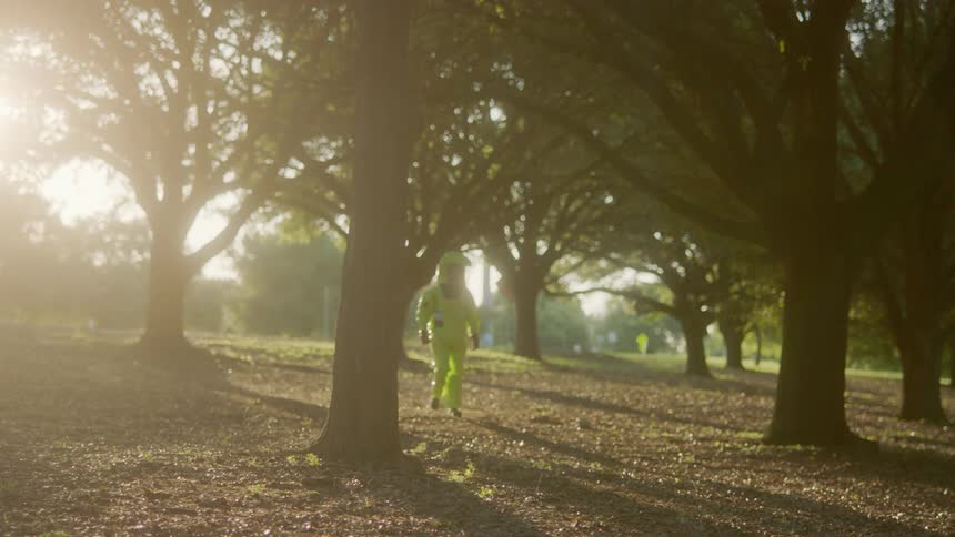 A man wearing protective gear walks past some trees