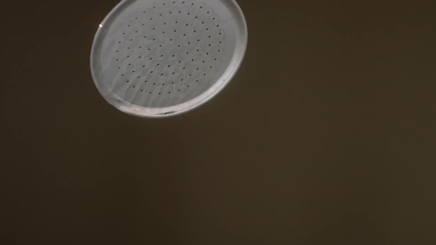 A silver shower head with water dripping off of it