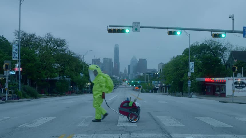 A man in a hazmat suit crosses the street