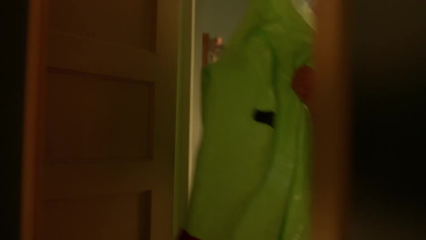 Person picks up protective suit from where it is hanging against bedroom door