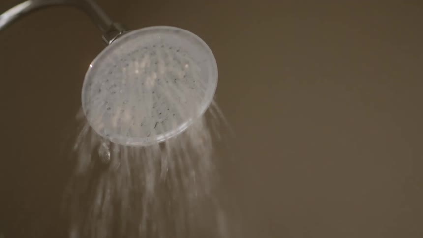 A silver shower head with water coming out of it