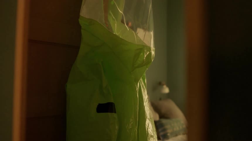 A person puts a hazmat suit on the door hook