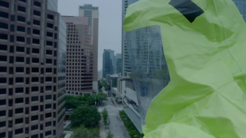 A man with a hazmat suit looking around with buildings in the background
