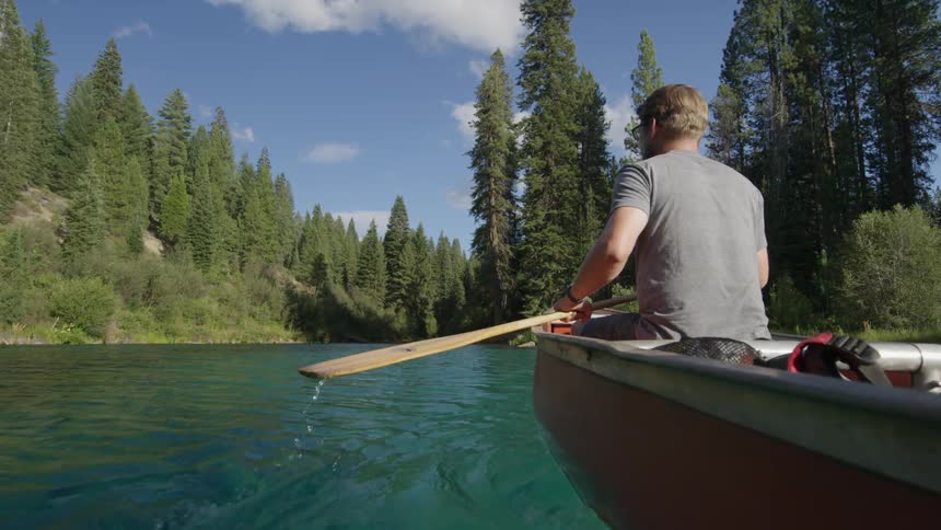 A man paddles through a clear water creek