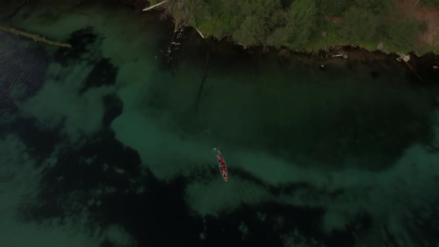 Two people kayak through clear water