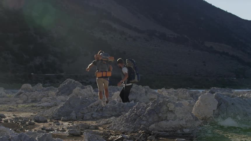 Two men are walking across what remains after a glacier came through long ago