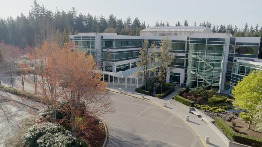 Ascending along the circle drive of a modern office building surrounded by trees on a sunny day