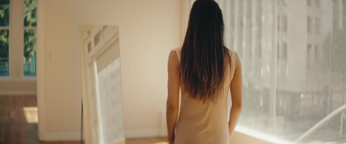A woman walks in her home looking out the window