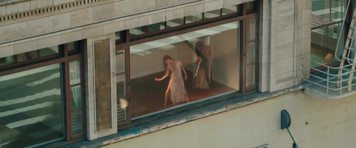 A woman is frozen still while dancing behind the window