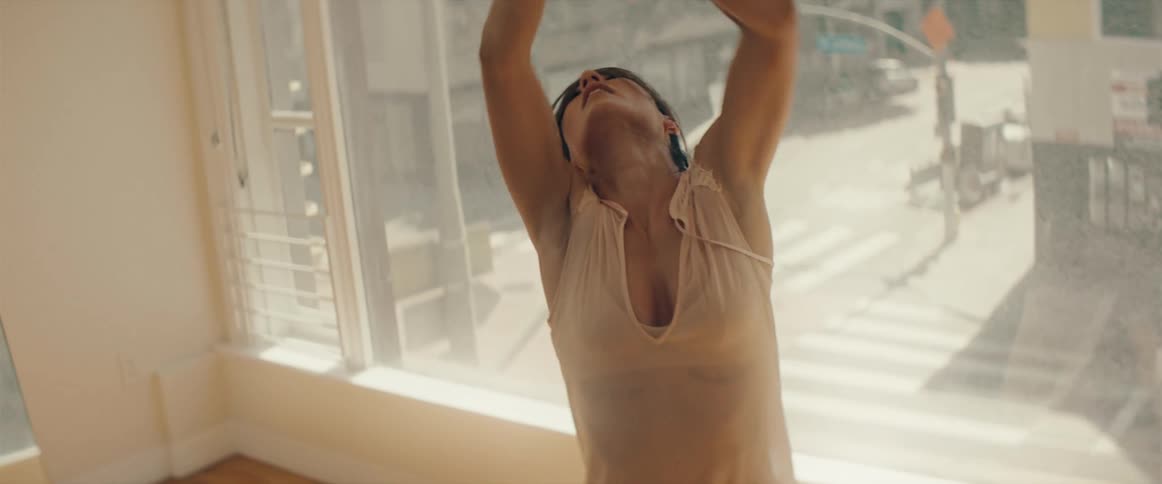 A woman dancing in a room with a large window and a mirror