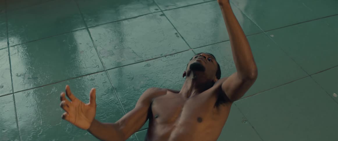 A man next to the floor made with green tiles shirtless