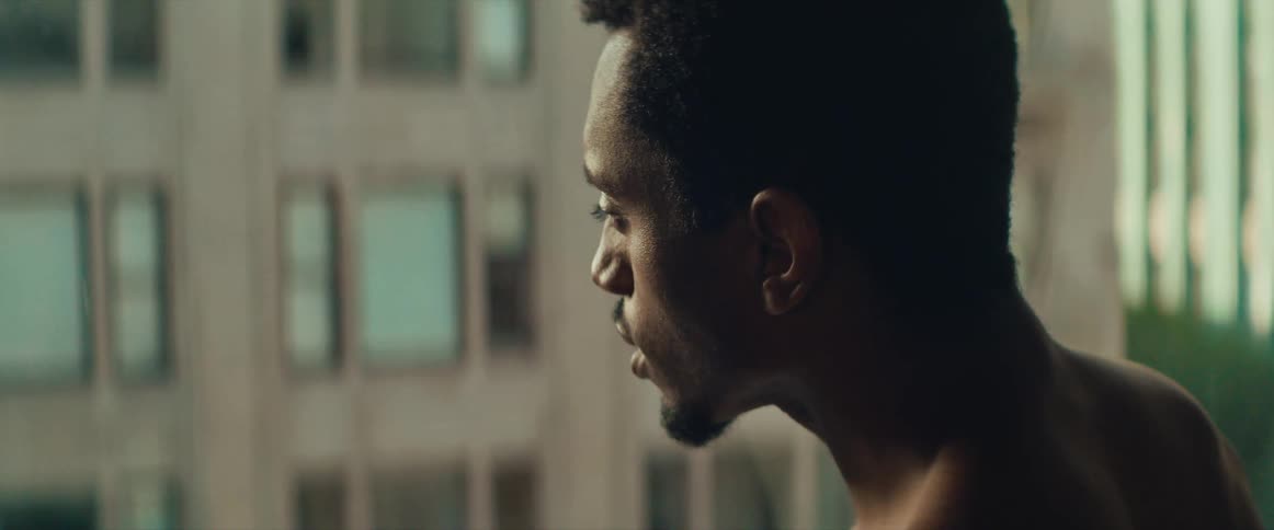 A man looks out the window to the building across from him
