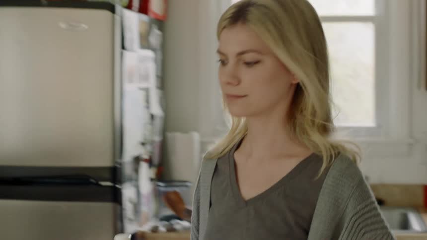 A woman carries a coffee pot in the kitchen