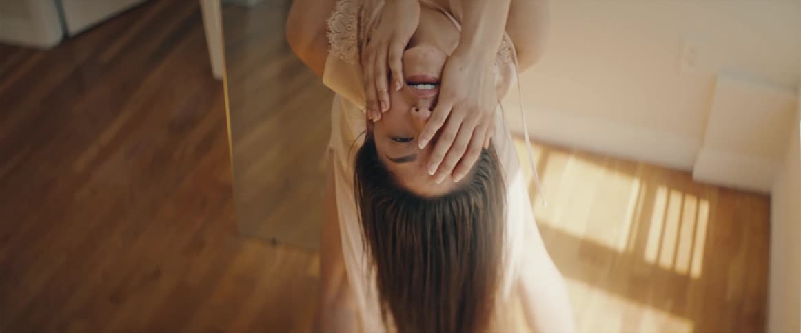 A woman is dancing and leaning back rubbing her face