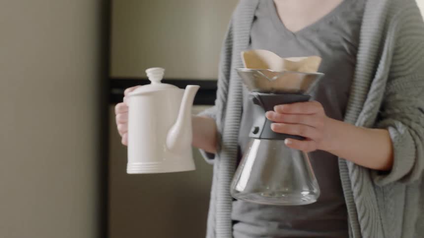 A woman begins to brew some coffee
