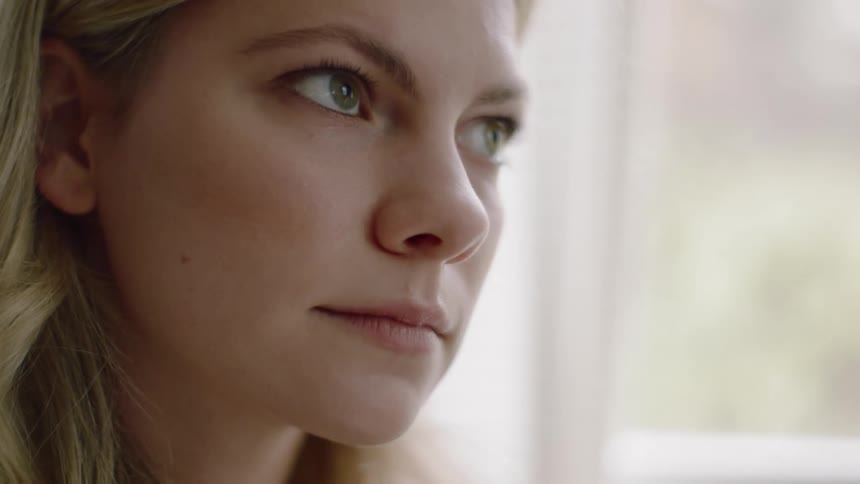 Blonde woman looks around and thinks about something indoors