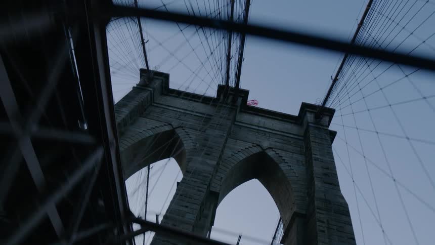 A large suspension bridge runs past buildings in a city