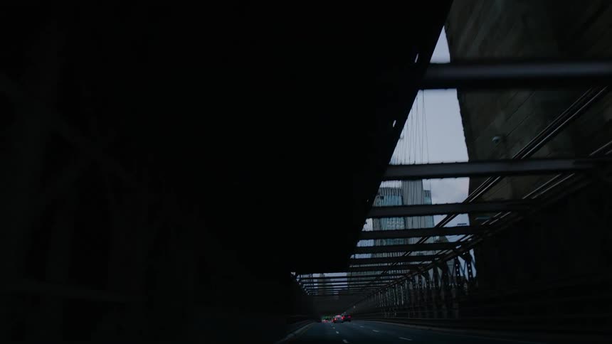 Cars are driving on a bridge near a downtown city