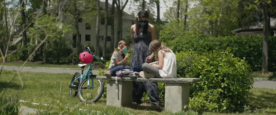 A woman sits with her children in the park
