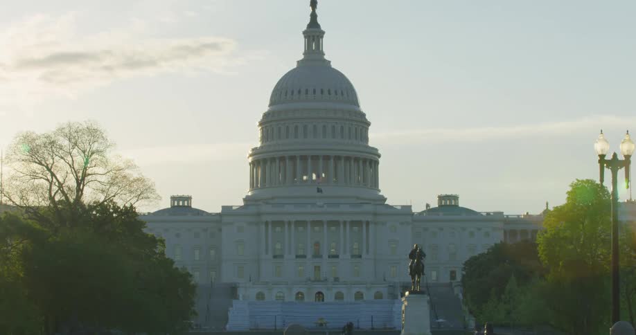 A woman runs past a capitol building as the sun starts to set